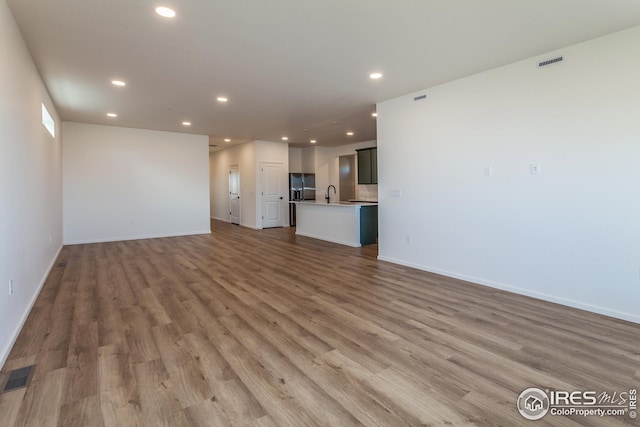 unfurnished living room featuring light hardwood / wood-style floors and sink