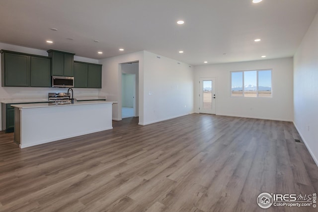 kitchen with range, a center island with sink, and light hardwood / wood-style flooring