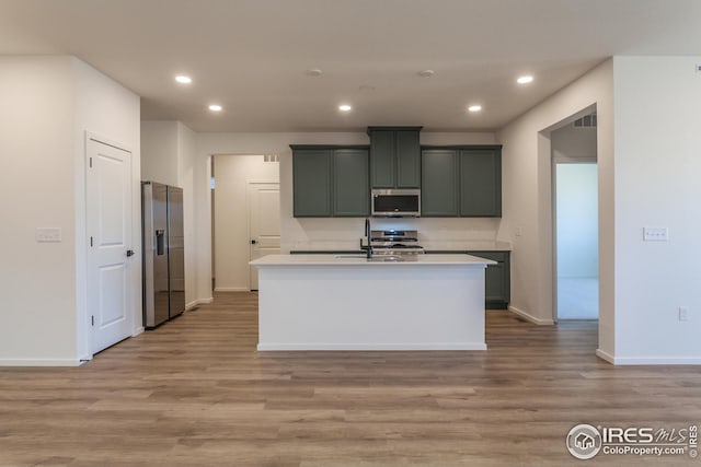 kitchen featuring light wood-type flooring, stainless steel appliances, and a kitchen island with sink