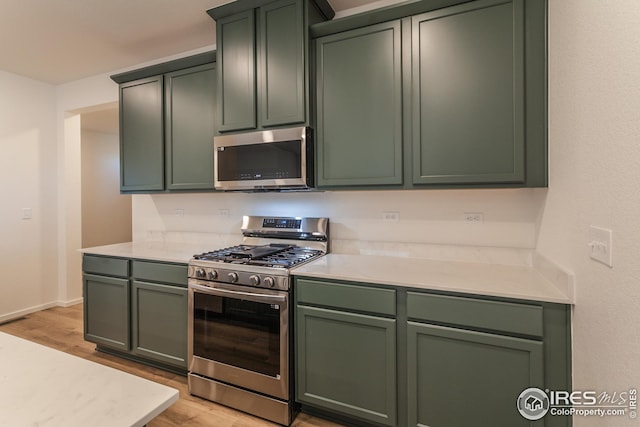 kitchen with light hardwood / wood-style floors, appliances with stainless steel finishes, and green cabinets