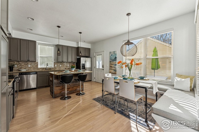 kitchen with appliances with stainless steel finishes, decorative backsplash, a breakfast bar, and light wood-style floors