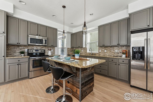 kitchen with stainless steel appliances, a sink, light wood-style flooring, and gray cabinetry