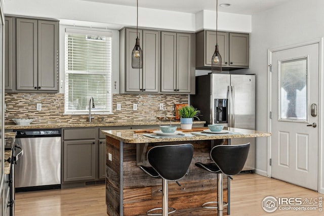 kitchen with stainless steel appliances, a sink, gray cabinetry, and tasteful backsplash