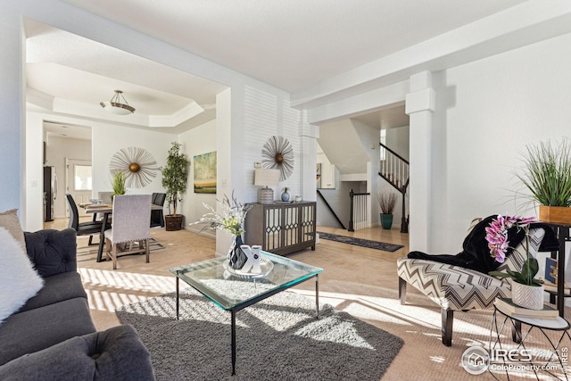 living room with stairs and a raised ceiling