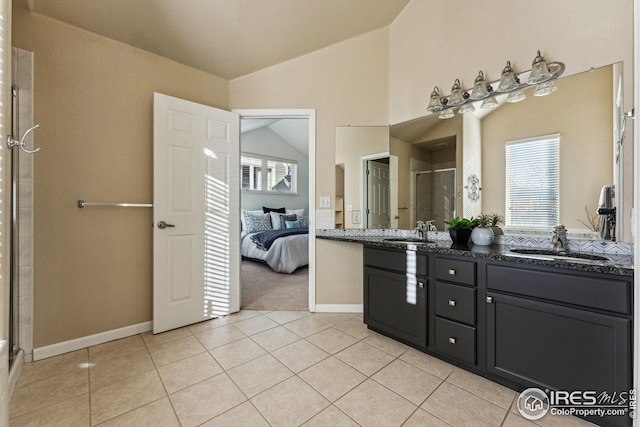 ensuite bathroom featuring a shower stall, vaulted ceiling, a sink, and tile patterned floors