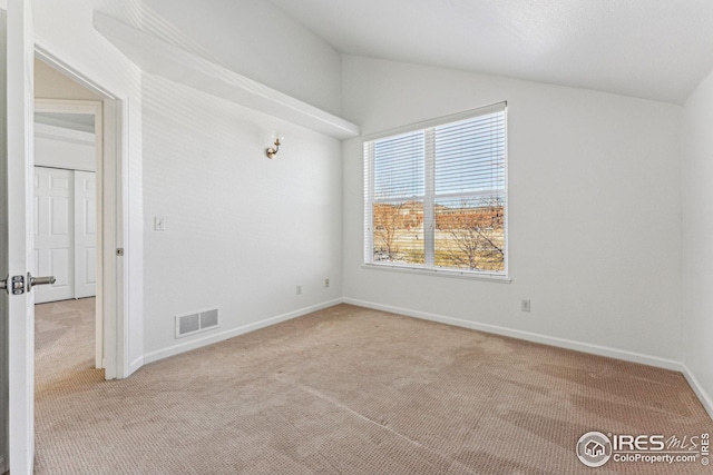 carpeted empty room featuring vaulted ceiling, visible vents, and baseboards