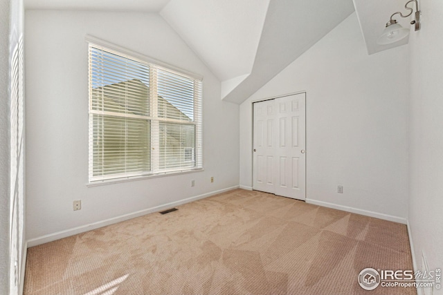 unfurnished bedroom with lofted ceiling, baseboards, visible vents, and carpet flooring