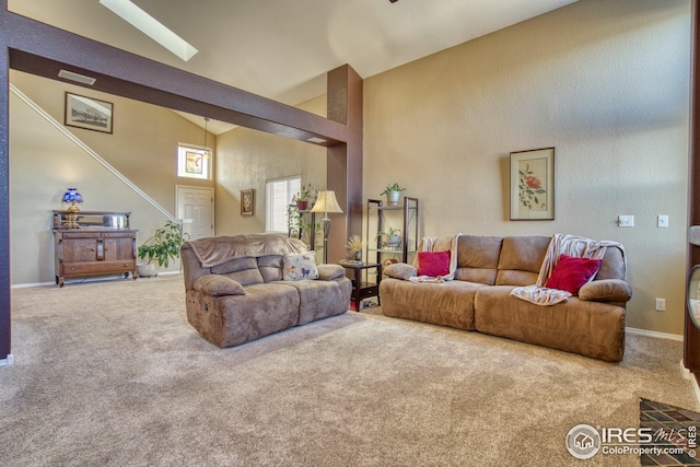 carpeted living room with high vaulted ceiling and a skylight