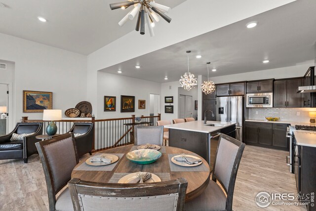 kitchen featuring sink, an island with sink, decorative light fixtures, light hardwood / wood-style floors, and a chandelier