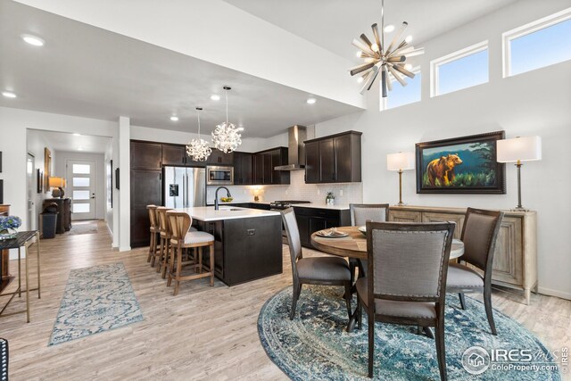 dining area featuring light wood-type flooring, a wealth of natural light, a notable chandelier, and sink