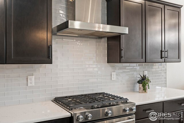 kitchen with sink, hanging light fixtures, stainless steel appliances, wall chimney range hood, and decorative backsplash