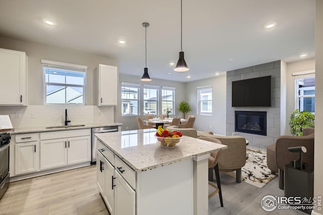 kitchen with white cabinetry, sink, dishwasher, pendant lighting, and a center island