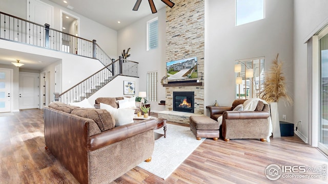 living room featuring stairs, a fireplace, plenty of natural light, and wood finished floors