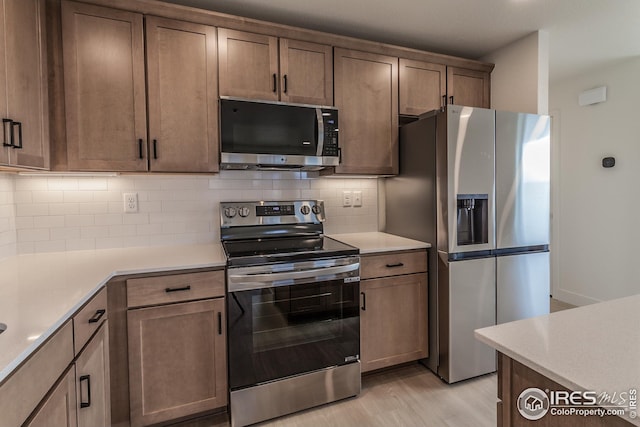 kitchen featuring decorative backsplash, light hardwood / wood-style floors, and appliances with stainless steel finishes