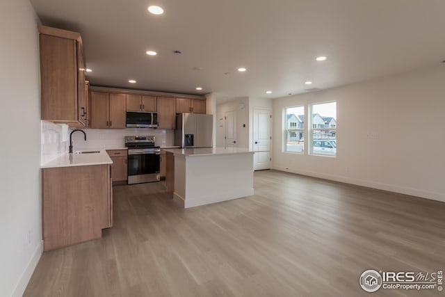 kitchen with light hardwood / wood-style flooring, a center island, stainless steel appliances, backsplash, and sink