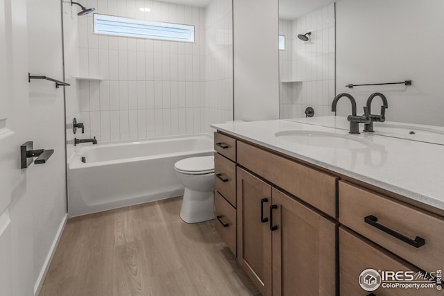 full bathroom with hardwood / wood-style floors, tiled shower / bath combo, vanity, and toilet