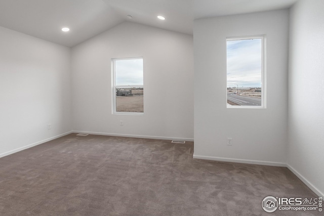 empty room with dark colored carpet and vaulted ceiling