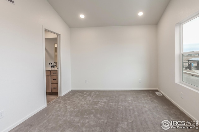 carpeted spare room featuring vaulted ceiling