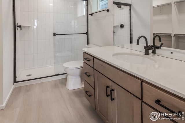 bathroom with toilet, a shower with door, vanity, and hardwood / wood-style floors