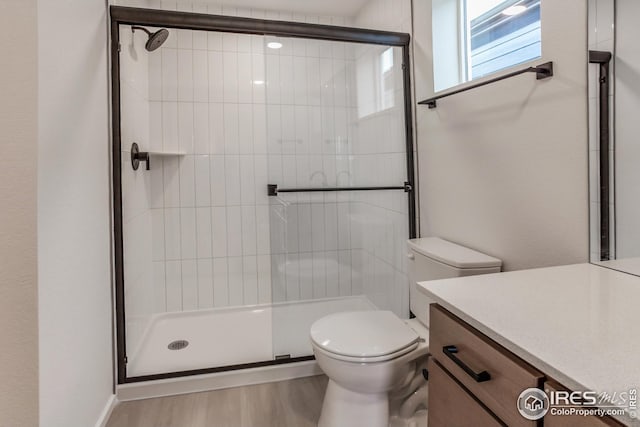 bathroom with toilet, a shower with door, vanity, and hardwood / wood-style floors