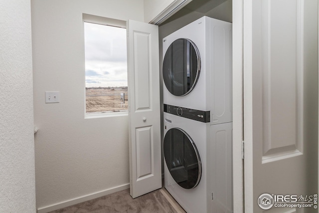 clothes washing area featuring stacked washing maching and dryer and carpet flooring