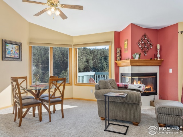 living room with lofted ceiling, a ceiling fan, a glass covered fireplace, carpet flooring, and baseboards