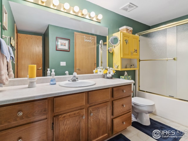 bathroom featuring tile patterned floors, visible vents, toilet, bath / shower combo with glass door, and vanity