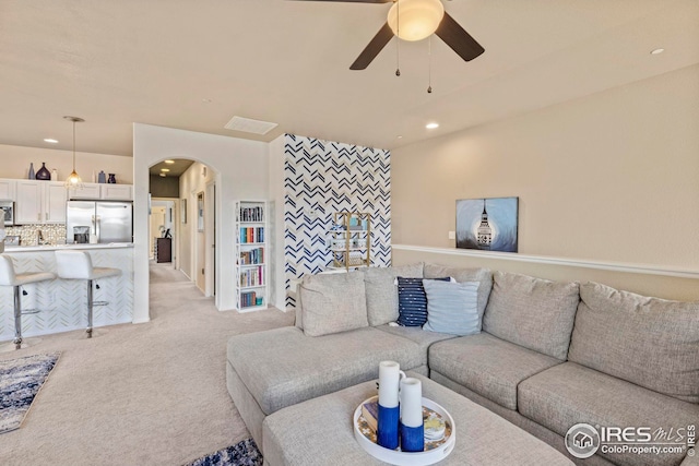 living room featuring recessed lighting, ceiling fan, arched walkways, and light colored carpet