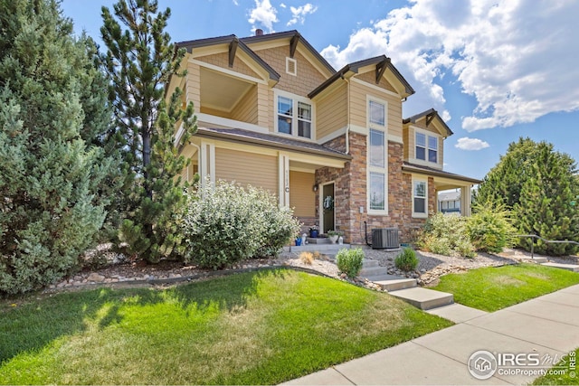 craftsman house with central air condition unit, stone siding, and a front yard