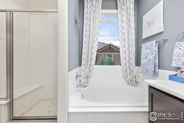 full bathroom featuring a bath, a stall shower, and vanity