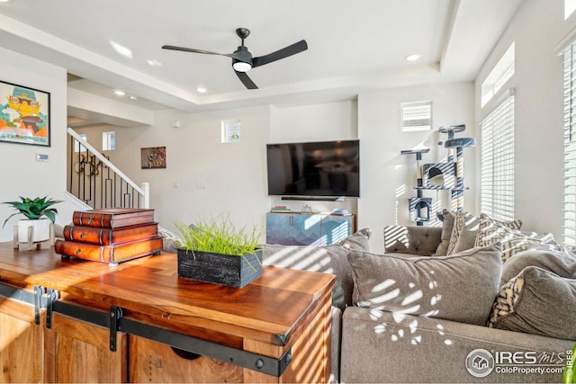 living room with ceiling fan and a raised ceiling