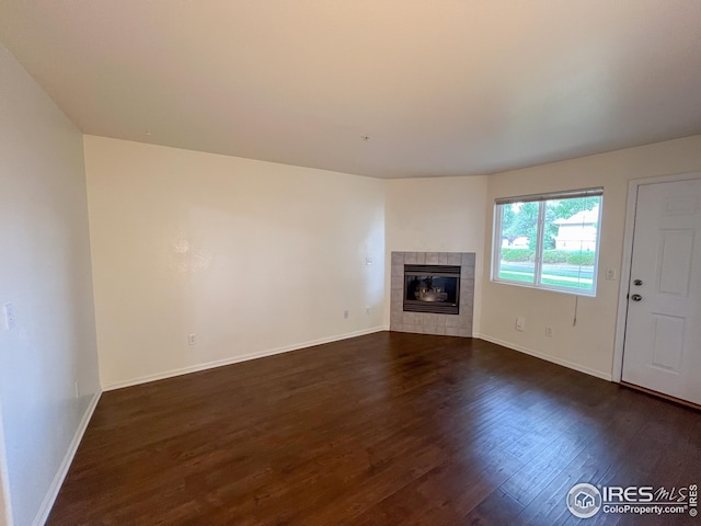 unfurnished living room featuring a tile fireplace and dark hardwood / wood-style flooring