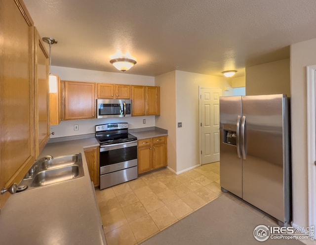 kitchen with sink, decorative light fixtures, a textured ceiling, light tile patterned floors, and stainless steel appliances