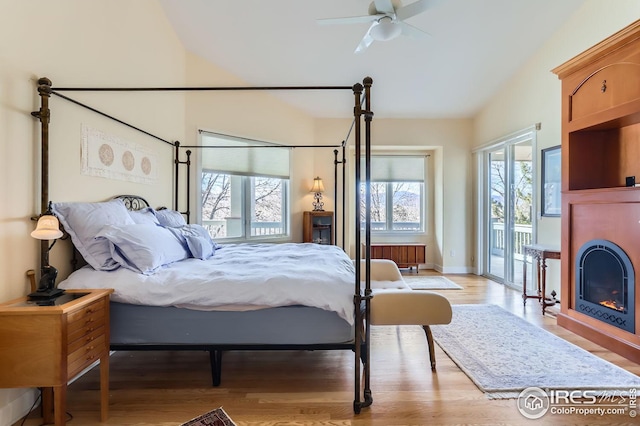 bedroom featuring multiple windows, radiator, access to outside, and light wood-type flooring