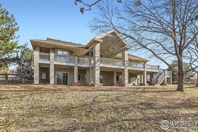 rear view of property featuring a balcony and a yard