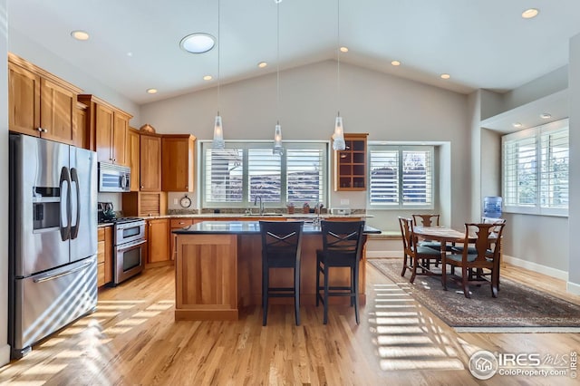 kitchen featuring a healthy amount of sunlight, appliances with stainless steel finishes, a kitchen bar, and a kitchen island