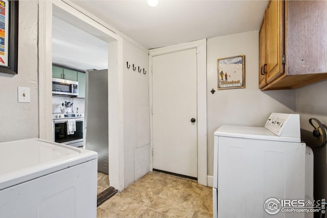 clothes washing area with cabinets and separate washer and dryer