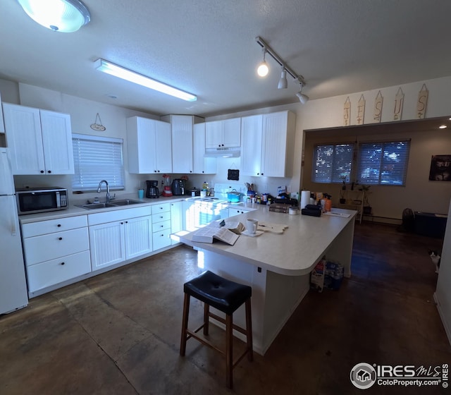 kitchen featuring white cabinets, sink, white appliances, and a breakfast bar area