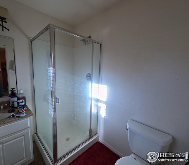 bathroom featuring toilet, an enclosed shower, and vanity