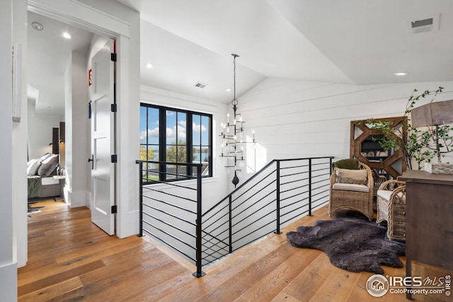 corridor featuring visible vents, vaulted ceiling, an upstairs landing, and hardwood / wood-style flooring