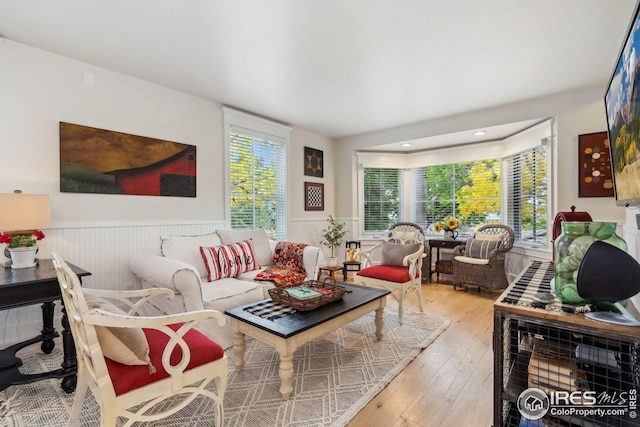 living area with a wainscoted wall, hardwood / wood-style floors, and a wealth of natural light