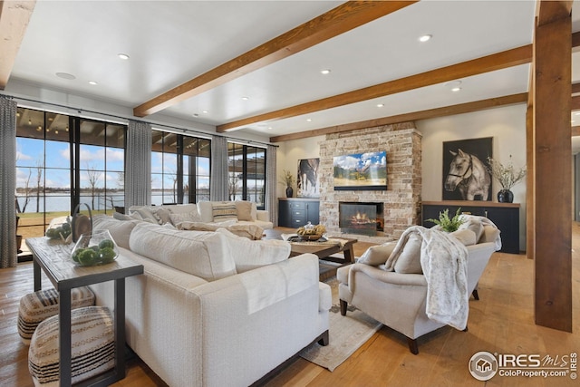 living room with recessed lighting, a fireplace, light wood-style flooring, and beamed ceiling