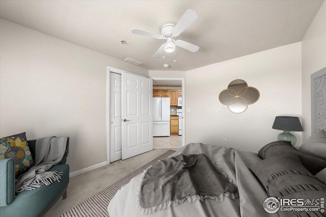 bedroom featuring light carpet, ceiling fan, white refrigerator, and a closet