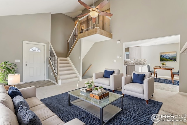 carpeted living room with ceiling fan and high vaulted ceiling