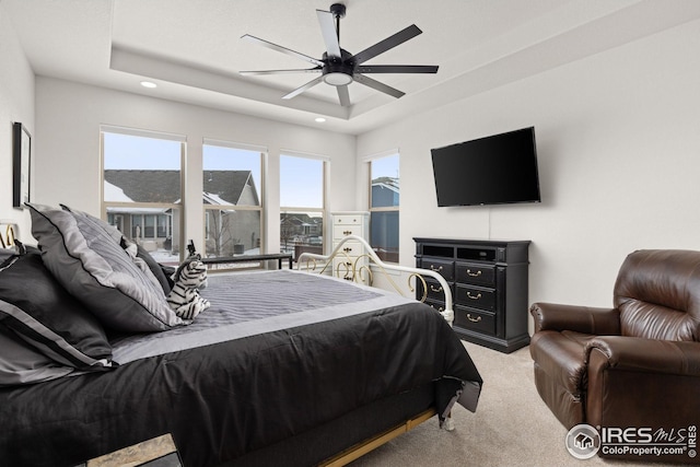 bedroom with ceiling fan, a raised ceiling, and light carpet