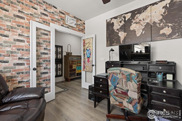 office area with brick wall and light wood-type flooring