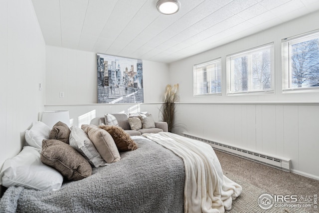 bedroom featuring a baseboard heating unit, wooden walls, and carpet