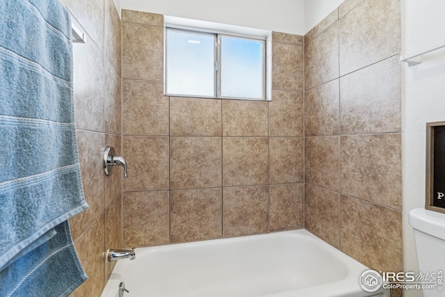 bathroom featuring tiled shower / bath and toilet