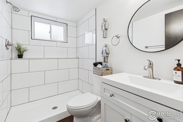 bathroom featuring tiled shower, vanity, and toilet