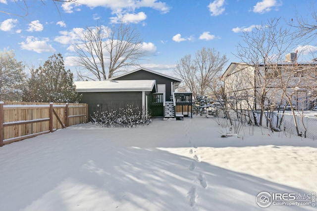 yard layered in snow featuring a carport